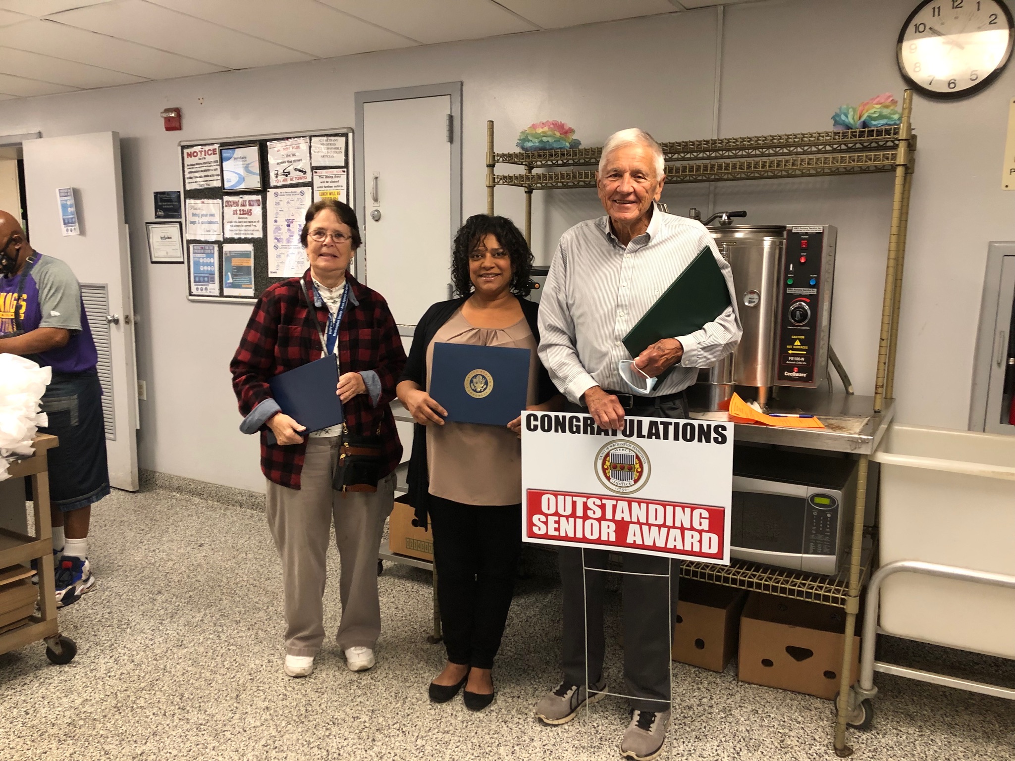 Dr. Eugene Witiak with sign that reads "Congratulations: Outstanding Senior Award" next to two women 