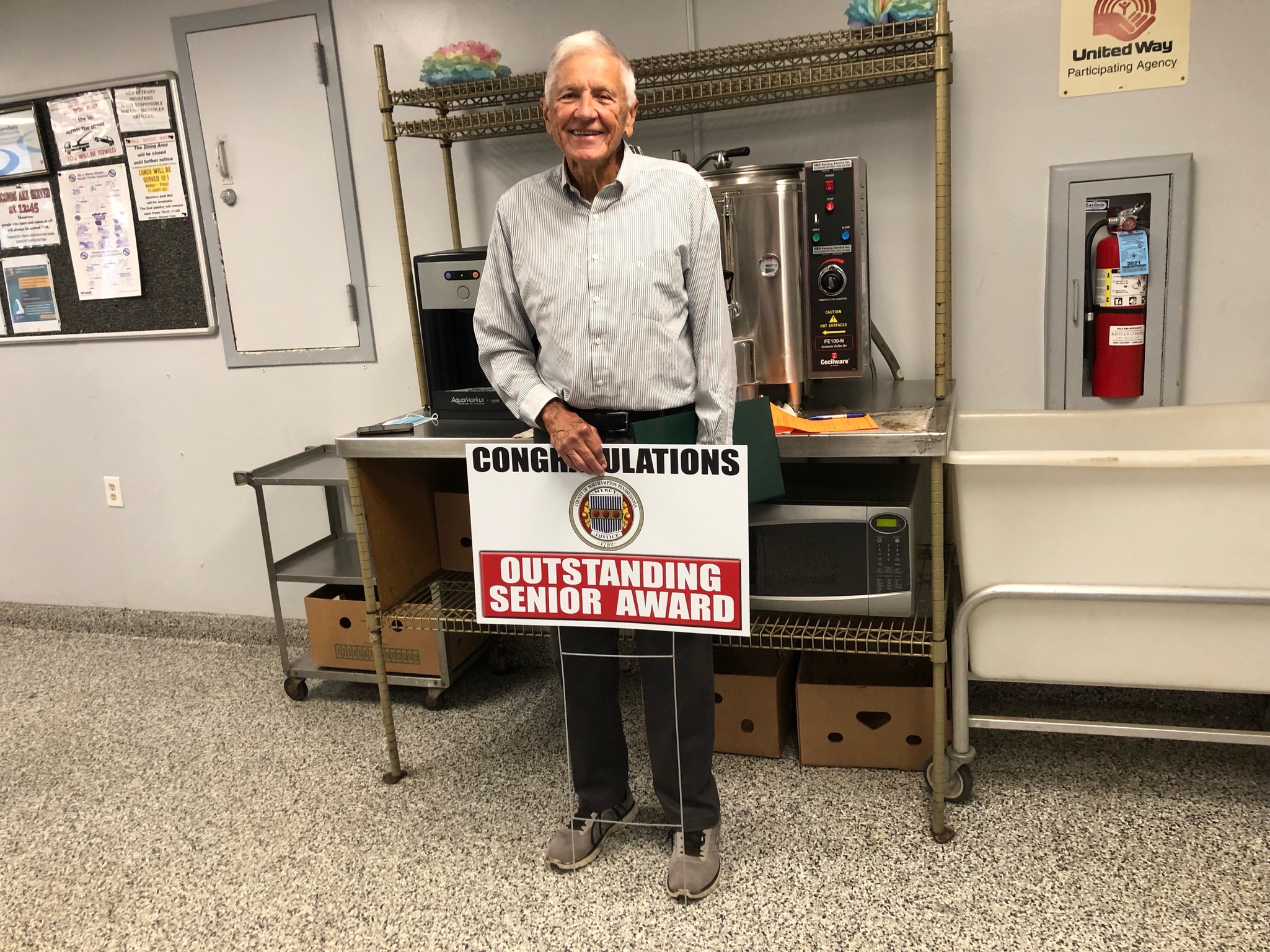 Dr. Eugene Witiak with sign that reads "Congratulations: Outstanding Senior Award"