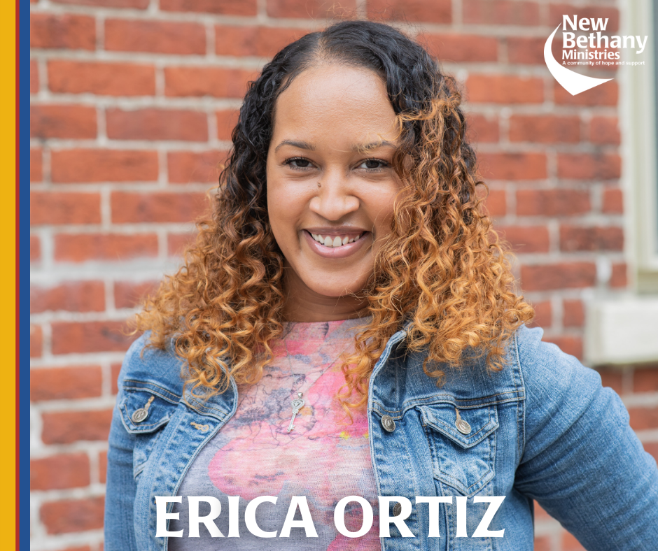 Erica poses for a headshot in front of a brick wall