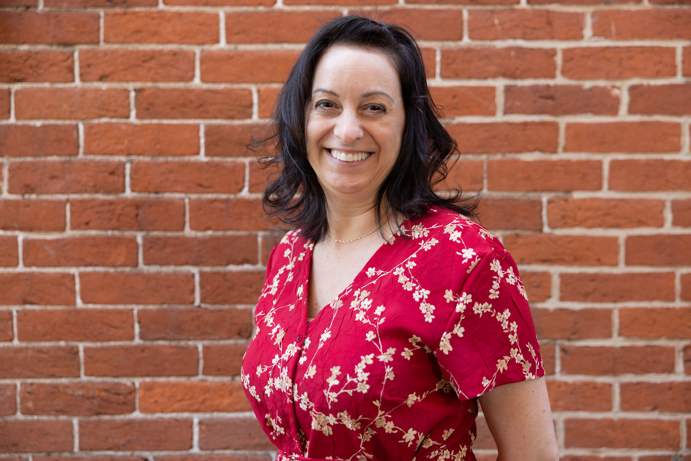 Kim poses for a headshot in front of a brick wall