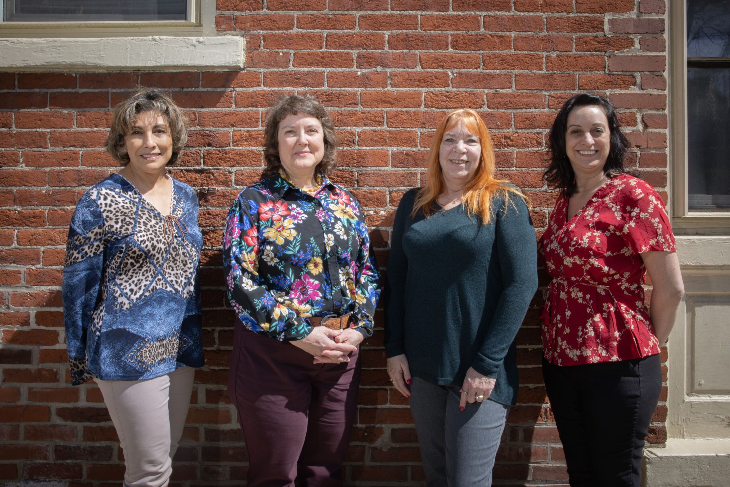 Four women standing in front of a brick wall.